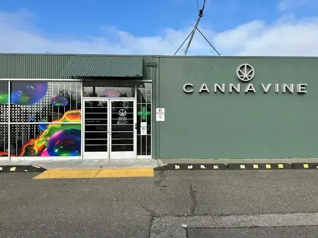 Cannavine dispensary exterior with green wall and colorful mural