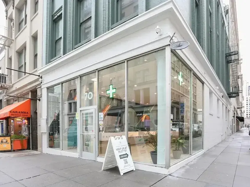 Corner storefront with glass windows and green cross sign
